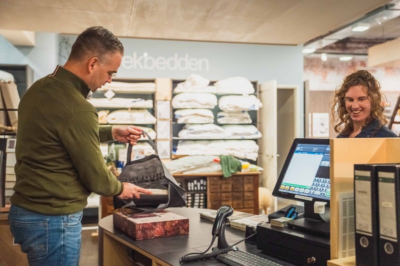 Einrichtungshaus-Mitarbeiter im Showroom mit digitaler Produktubersicht auf dem Bildschirm